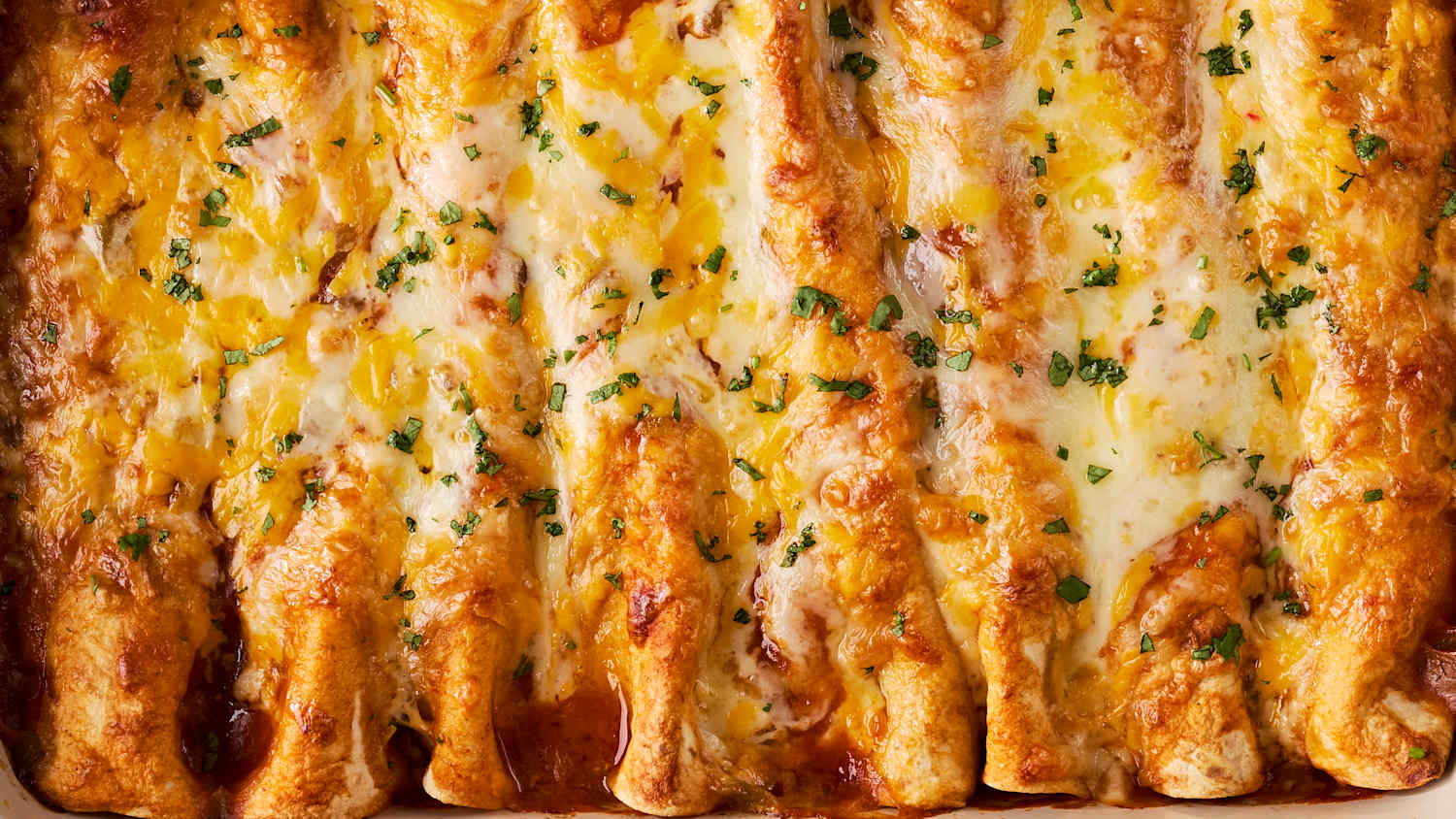 A glass baking dish of enchiladas being placed into a hot oven on an oven rack