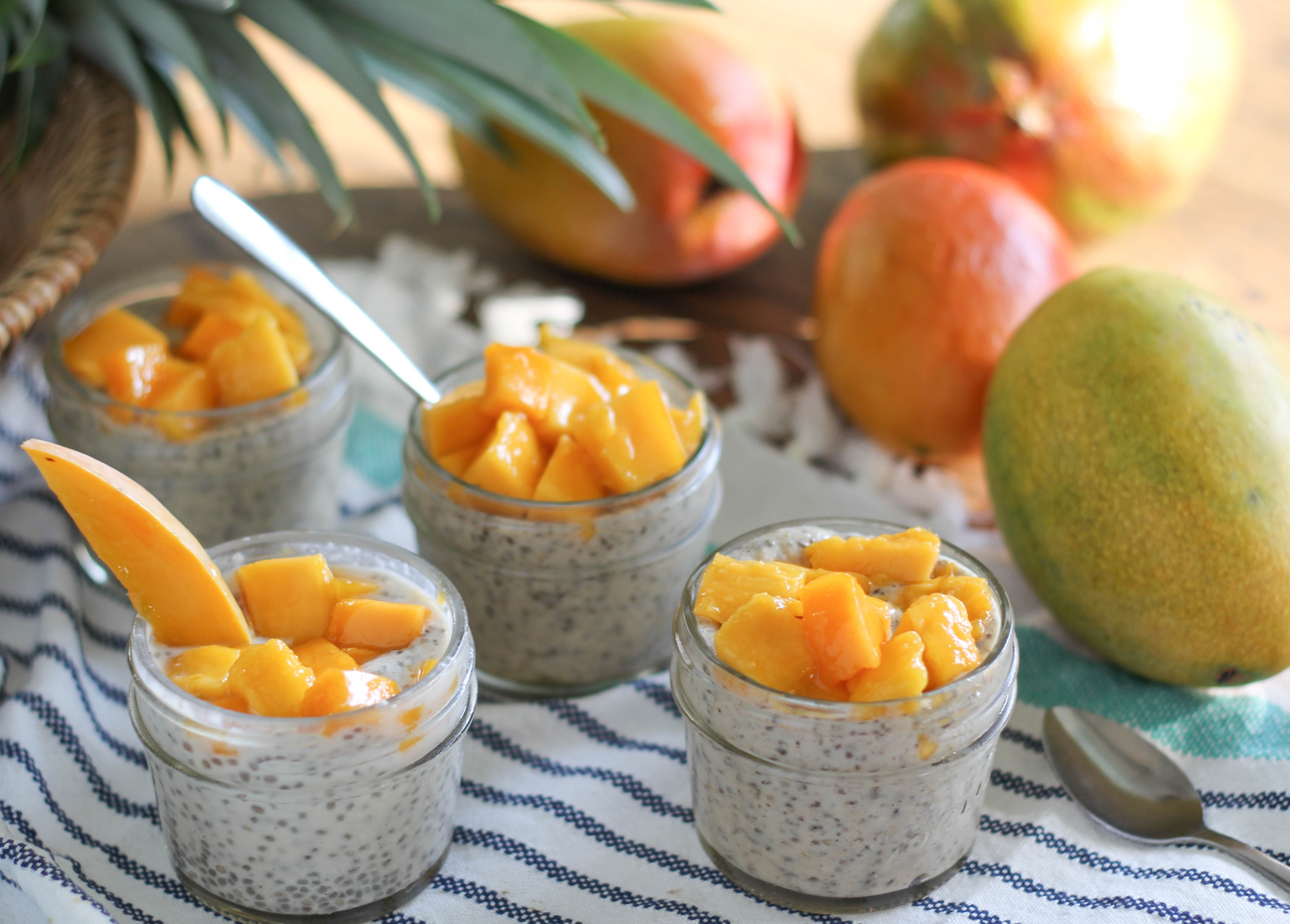 A small glass jar of coconut chia pudding topped with bright orange mango pieces
