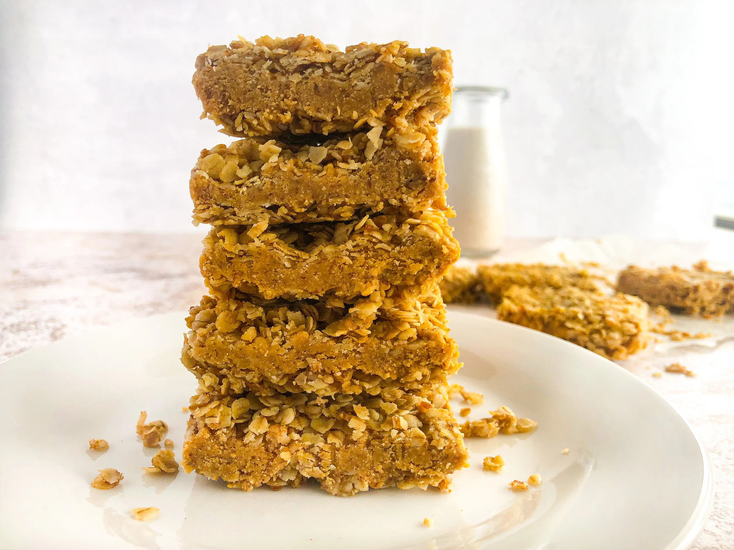 A small stack of no-bake peanut butter oat bars on a plate, showing chewy oat layers and a glossy chocolate top